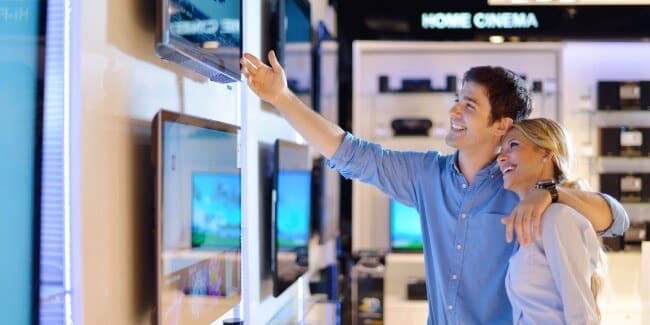 Two shoppers looking at televisions in an electronics store